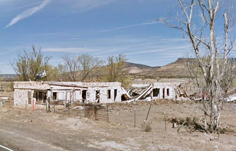 Mt. Taylor Motel ruins in 2014 Cubero NM motel, vacant and in ruins seen from Route 66, single story narrow block shaped building perpendicular to US66