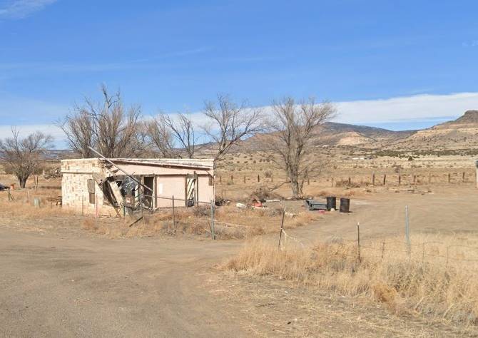 Mt. Taylor Motel ruins in 2021 Cubero NM motel, vacant and in ruins seen from Route 66, single story narrow block shaped building perpendicular to US66