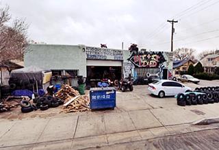 4th St. Navajo Super Service Station box shaped building, service bay to the left, grafitti and old tires piled up. Office on the right, seen from Route 66