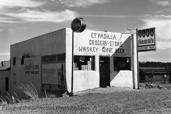 Padilla Store in 1971, Rowe NM by David Noble Black and white, 1971, block shaped white building facing higwhay, signs painted on walls, sells liquor, wine, beer