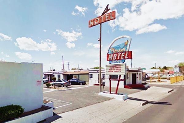 motel with a classic red and blue neon sign including and arrow flanked by a tall sign with the word MOTEL in white letters on a red background