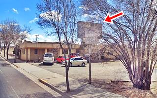 former Pueblo Courts motel Route 66 Grants NM former motel building, cars and old neon sign hidden in tree branches