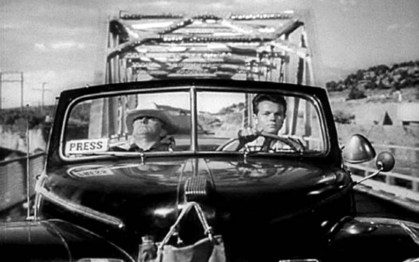 black and white still from movie ACE IN THE HOLE showing convertible car, two men in it, bridge behind 1951