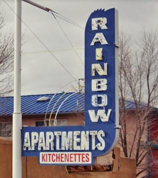blue L shaped neon sign with white letters spelling RAINBOW Apartments facing Route 66