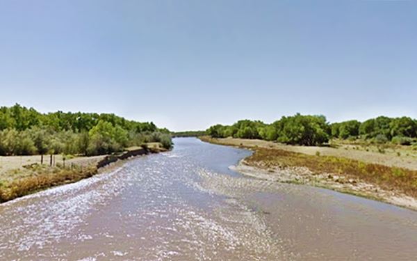 Rio Grande runs between wooded banks, blue sky
