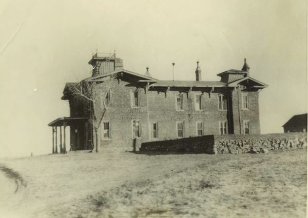 Sepia 1900s photo two story large mansion with turrets