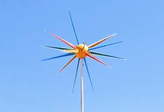 ball with colored spokes atop a pole, blue sky behind, a rotosphere