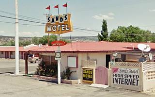 Sands Motel nowadays, Grants NM US66 motel office with a yellow neon sign topped with 3 flags