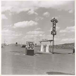 Ed Ruscha (c) 1962 picture of Self Service station on Route 66 in Milan NM black and white photograph 1962 by Ed Ruscha, showing a set of self service pumps under sign indicating price 26 cents. Hills in the distance, Route 66 behind