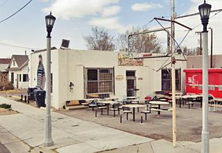 4th St. SW Sinclair box shaped building, a former Gas station on a corner, neon sign empty, tables and chairs in the parking area no pumps, seen from Route 66