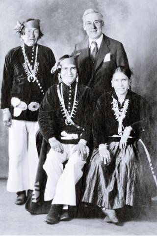 B. I. Staples and Navajos c.1930s Berton Isaac Staples standing (right) and three Navajos craftsmen, two seated (one is a woman) one standing all in traditional clothes; black and white photo c.1930s