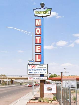 Slender neon sigh, topped with figure with word GARDENIA in it, and vertical red boxess with white letters spell MOTEL