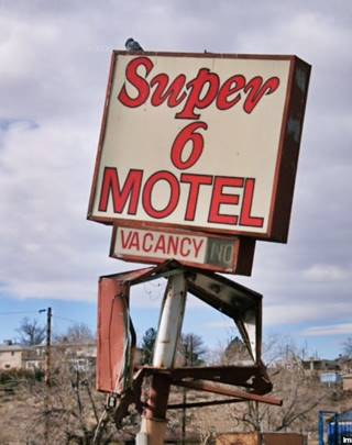 faded box shaped red sign twisted metal with white letters spelling SUPER 6 MOTEL seen from Route 66