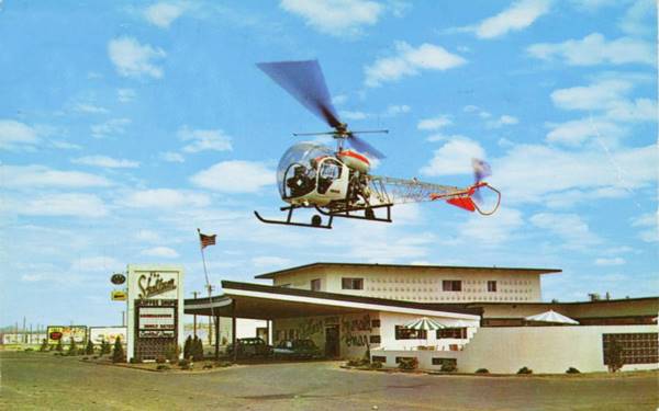 color 1960s postcard, motel lobby with a canted semicircular canopy held by slender steel poles, cars parked by lobby. Neon sign