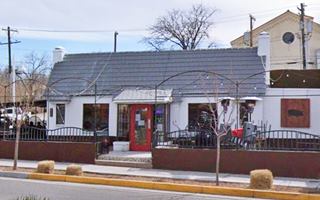 white gable roof building, central entrance door, windows to the side, US 66 runs left to right in front