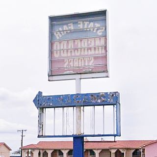 decaying neon sign with arrow, empty upper rectangle and word Vacancy on a faded peeling blue background