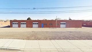 long 1 story, Pueblo style, brown colored garage with 4 service bays and central office windows and door seen from Route 66