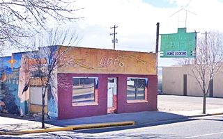 2021 view Uranium Cafe, Grants, New Mexico color picture box shaped single floor cafe, green neon sign to the right, Route 66 in front