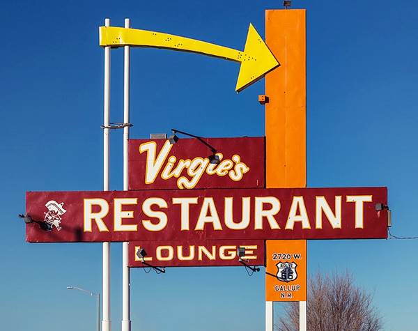 red neon sign with a yellow arrow orange vertical panel. VIRGIE’s RESTAURANT LOUNGE in white letters