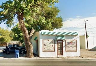 White Cafe block shaped building, flat roof, central door, windows on each side, tree to the left