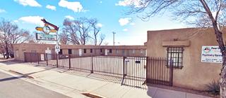 Zia Motel nowadays US66 Grants NM beighe adobe-Pueblo style motel with neon sign, steel fence closes courtyard