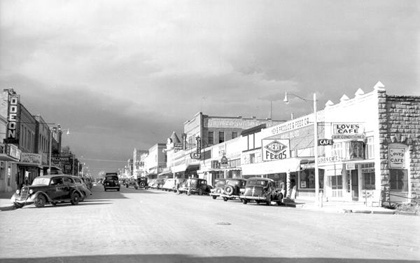 black and white photo from 1940 with cars, buildings and stores, looking north along Route 66 in Chandler