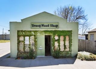 1920s garage on old US66 Tulsa green building, with glass windows on each side of entrance, gable roof, brick.