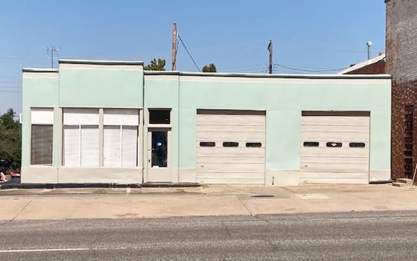 one story flat roof old gas station painted pastel green