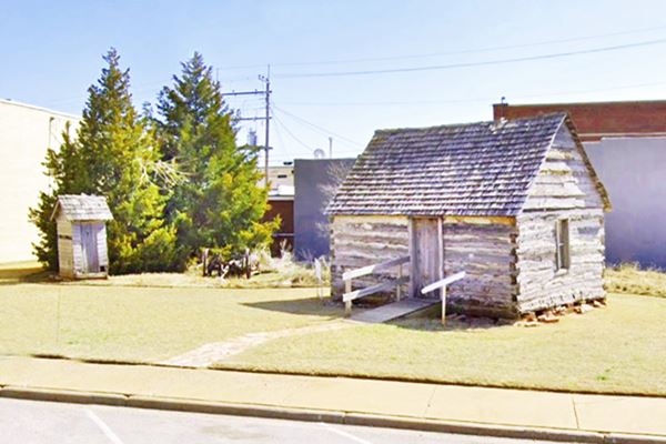 ancient log cabin with gable roof and outhouse, Weatherford Oklahoma