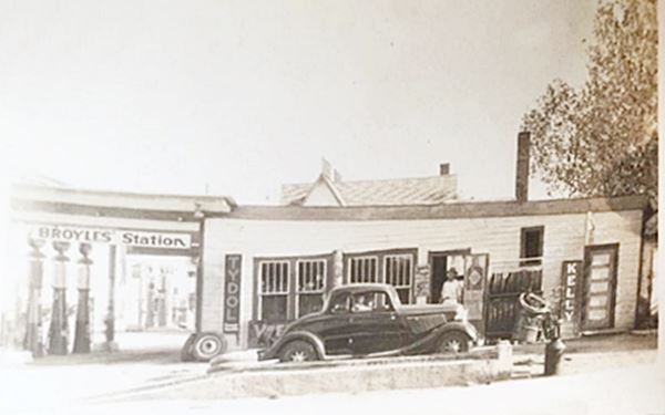 1930s car at gas station, tires, people and gas pumps. Black and white picture