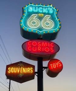 neon sign lit at night topped by US66 shield and panels with oval, circle and hexagonal shapes