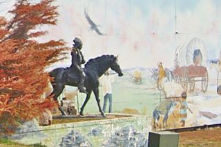 bronze Cherokee on a horse statue by mural