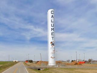 tall tube-like water tower painted white with inscriptions
