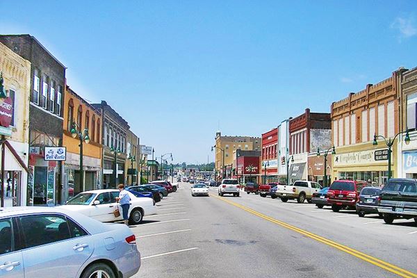cars, people, old red brick buildings line Main St. in Claremore