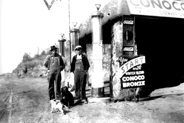 black and white photo, men, gas pumps and rock building 1920s gas station