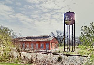 red brick building and steel water tower next to railroad tracks