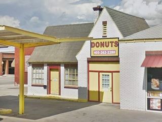 cottage stlye gas station with gable roof and bricks painted white with detched yellow canopy