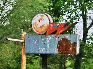 rusty sign with W shaped lightning on the top by a circle