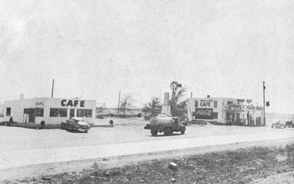 1948 view of cars on US 66, cafe and gas station in a black and white photo