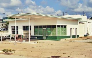 former 1950s gas station Tulsa former icebox gas station, glazed office right, 2 service bays left flat canopy over pump islands, garage in the rear painted white and green