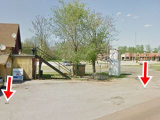 site of Arcadia Gibble gas station paved parking area, tree and building