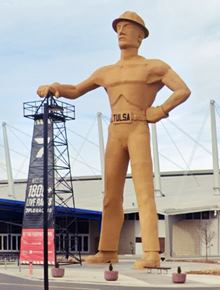 Giant yellow statue of oil drill worker hand on top of an oil rig