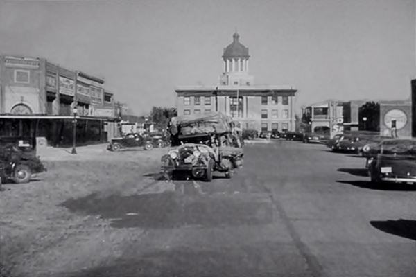 still from The Grapes of Wrath shot in Sayre, the Joads truck and the Courthouse behind