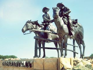 bronze statue of two cowboys shaking hands