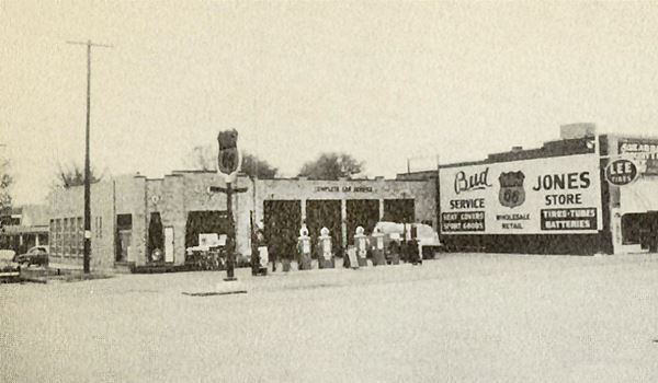 brick gas station on corner in black and white 1954 advertisement