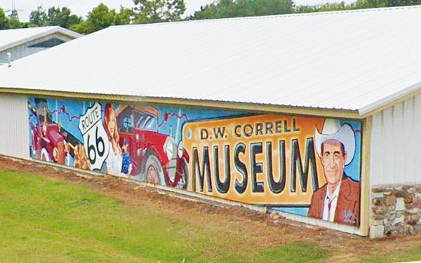 Mural, man, cars, US66 shield outside of the D.W. Correll Museum, Catoosa, OK.