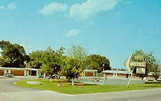motel, lawn, pool, neon sign on the right reads MOTEL OASIS, 1950s color postcard, Route 66 runs in front