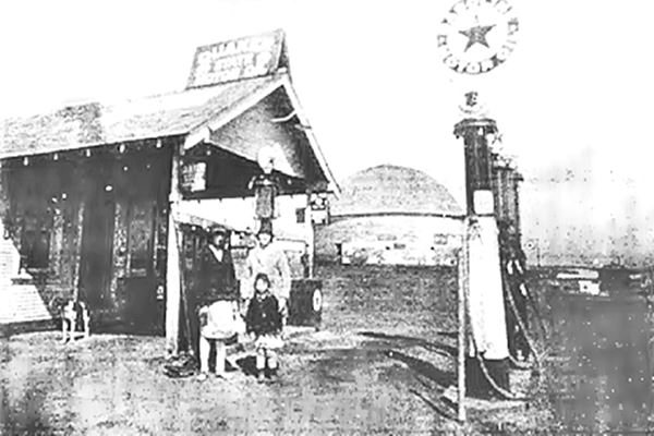 1920s view of Texaco gas station and round barn, black and white photo