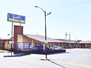 gable-roof brick motel, cars by office, neon sign