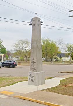 concrete obelisk on sidewalk by US66
